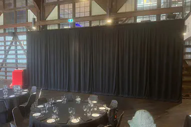 Black event draping used behind round dining tables in a large indoor function space